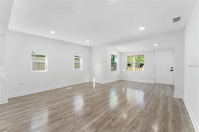 an empty room with wooden floor and windows