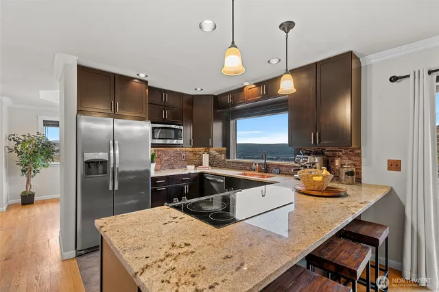 a kitchen with a refrigerator a sink a stove and chairs