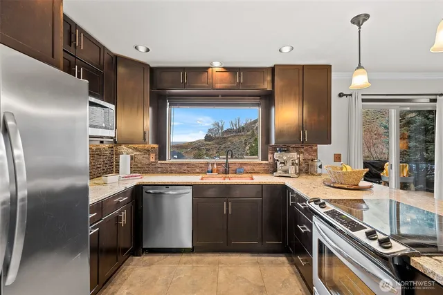 a kitchen with stainless steel appliances granite countertop a sink a stove and a refrigerator