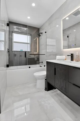 a bathroom with a double vanity sink a toilet a mirror and bathtub