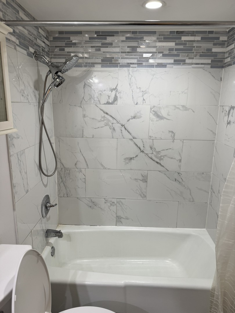 6027 103rd Street, Unit 1A Chicago Ridge, IL 60415 - Photo 3 of 7 a bathroom with a shower and a bath tub