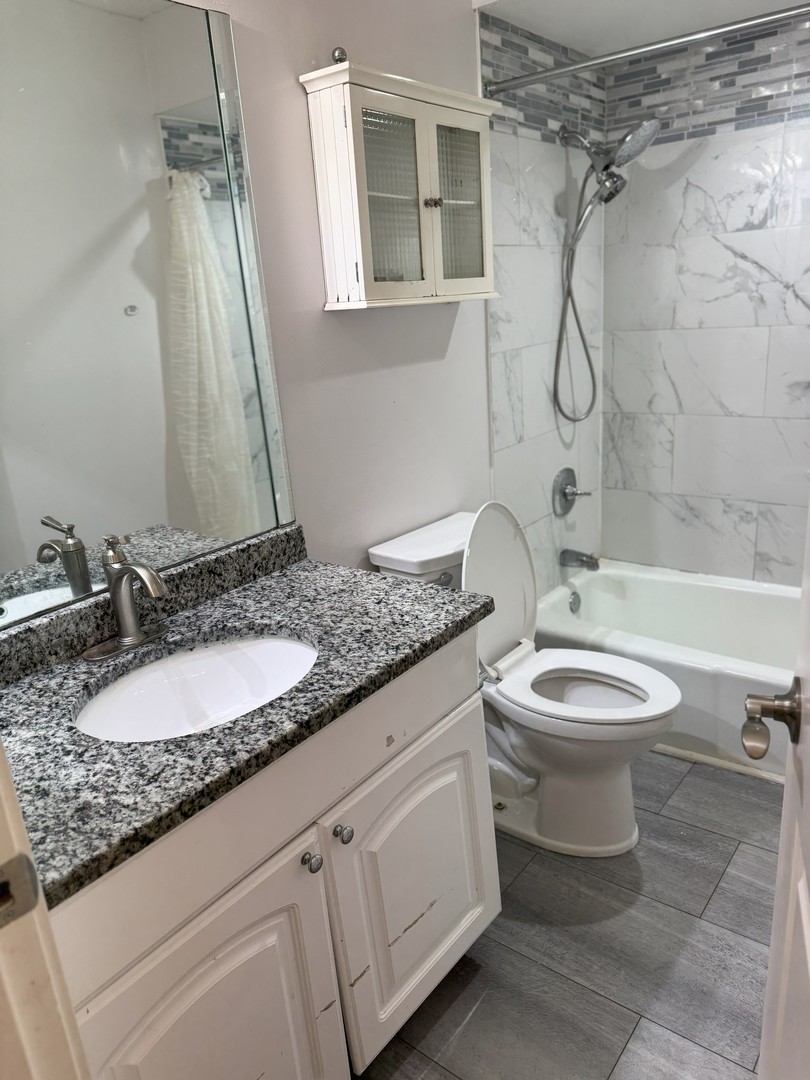 6027 103rd Street, Unit 1A Chicago Ridge, IL 60415 - Photo 4 of 7 a bathroom with a granite countertop sink toilet a mirror and shower