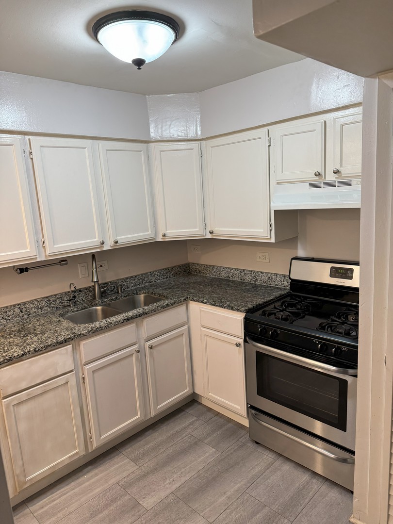 6027 103rd Street, Unit 1A Chicago Ridge, IL 60415 - Photo 5 of 7 a kitchen with granite countertop white cabinets and appliances
