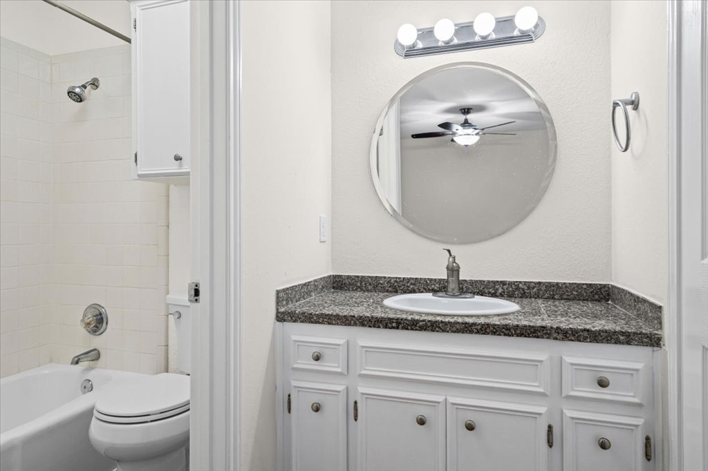 361 Fantail Loop, Unit B Austin, TX 78734 - Photo 18 of 29 a bathroom with a granite countertop toilet a sink and a mirror