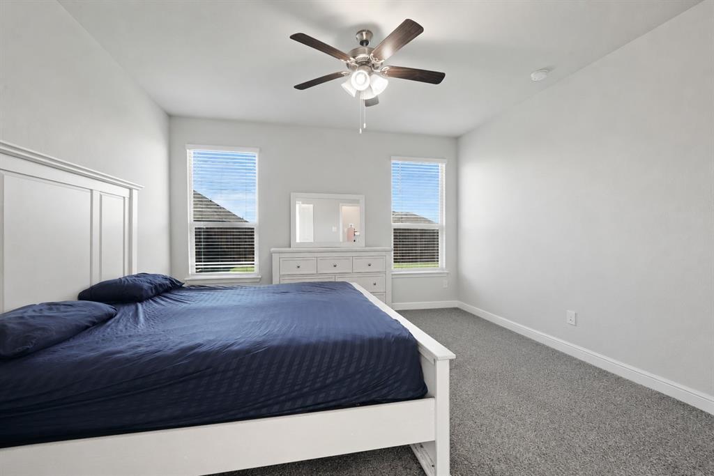 1112 Croxley Way Justin, TX 76247 - Photo 7 of 18 Bedroom featuring vaulted ceilings, a ceiling fan with light fixture, two windows with blinds, and gray carpet flooring