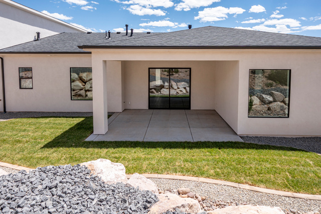 2862 South Mountain Rnch Road Cedar City, UT 84720 - Photo 51 of 64 Rear exterior featuring a covered concrete patio, black-framed sliding glass door, and dark-framed windows