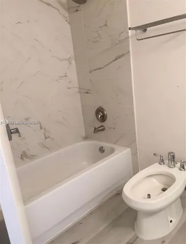 a bathroom with a white bath tub a sink and a toilet