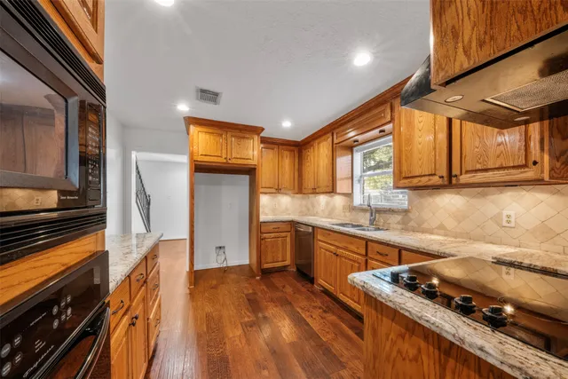 a kitchen with stainless steel appliances granite countertop wooden cabinets a sink and dishwasher a stove with wooden floor