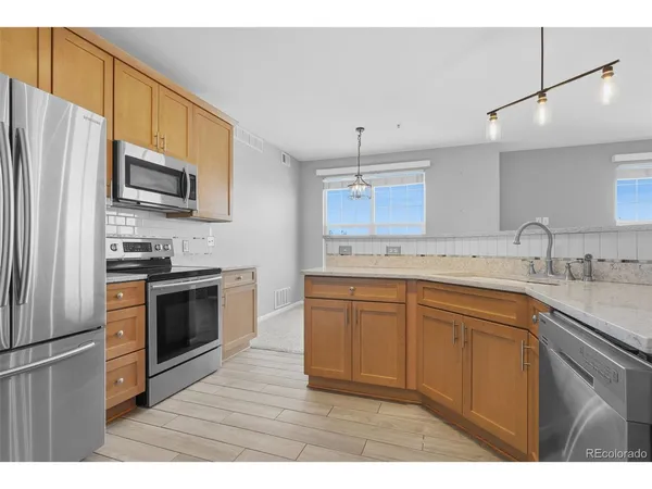 a kitchen with granite countertop a refrigerator stove top oven and sink