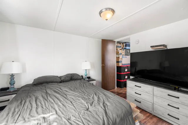 a bedroom with a bed and a flat tv screen on dresser