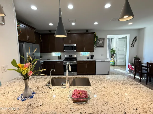 a kitchen with stainless steel appliances kitchen island granite countertop a sink a stove and a refrigerator