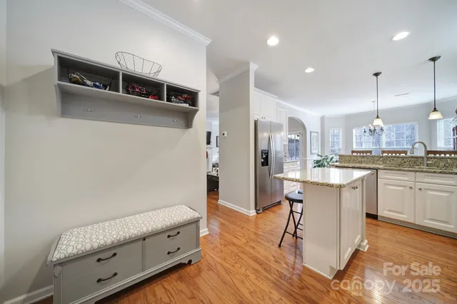 a kitchen with stainless steel appliances granite countertop a refrigerator a sink and white cabinets