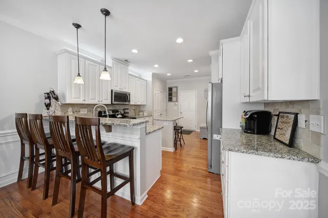 a kitchen with stainless steel appliances granite countertop a stove top oven a refrigerator a sink and chairs