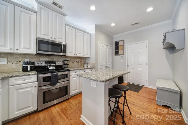 a kitchen with granite countertop a stove and white cabinets