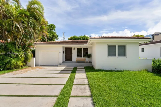 a front view of a house with a yard and potted plants
