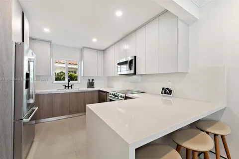 a kitchen with a sink a stove a refrigerator and white cabinets