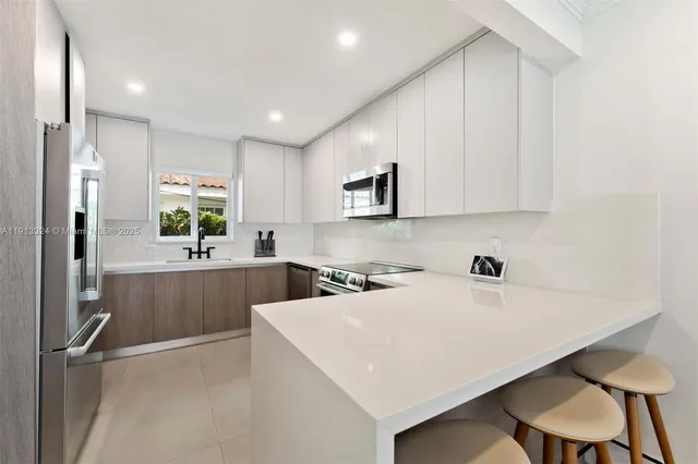 a kitchen with a sink a stove a refrigerator and white cabinets