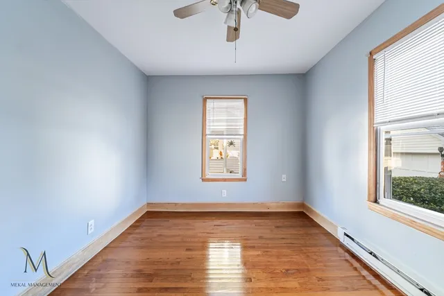 a view of empty room with wooden floor and fan