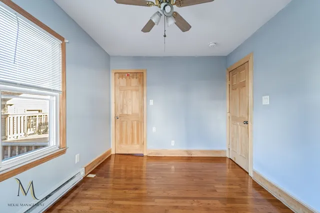 a view of an empty room with a window and wooden floor