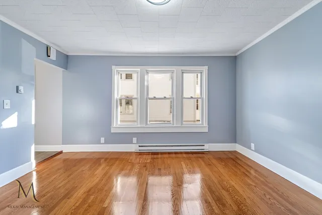 a view of an empty room with window and wooden floor