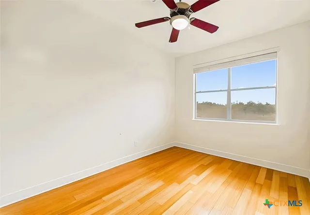 an empty room with a window and ceiling fan