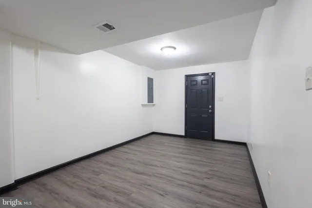 a view of an empty room with wooden floor and closet