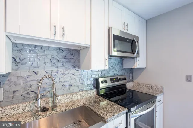 a kitchen with granite countertop a stove and a microwave