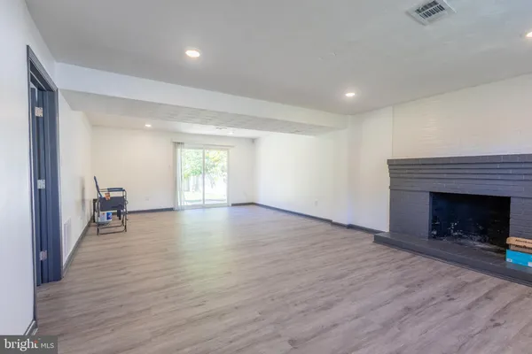a view of empty room with wooden floor and fireplace