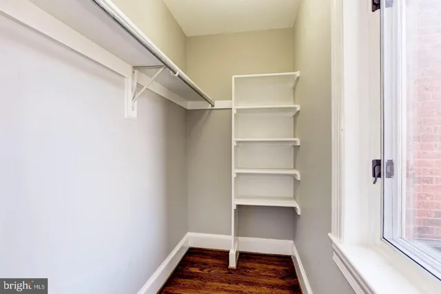 a walk in closet with wooden floor