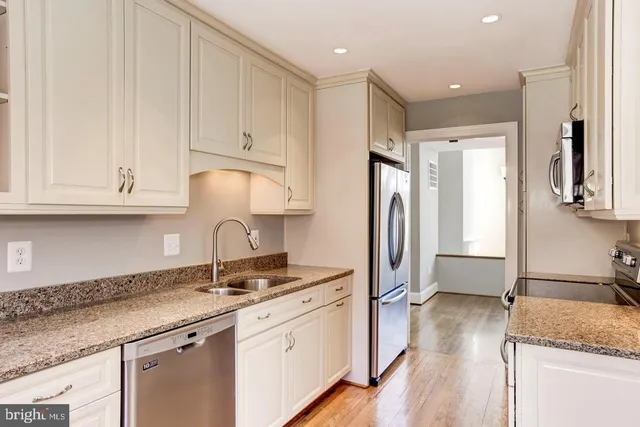 a kitchen with granite countertop a sink stainless steel appliances and cabinets