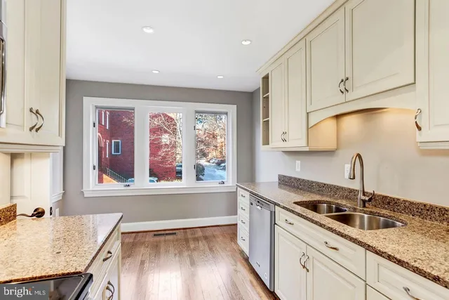 a kitchen with granite countertop a sink a stove and cabinets