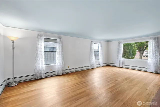 an empty room with wooden floor and windows