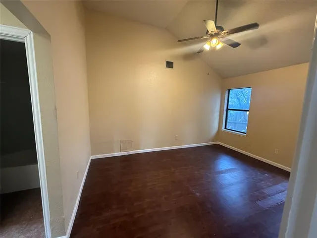 an empty room with wooden floor fan and window