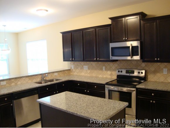 717 Sun Road Aberdeen, NC 28315 - Photo 4 of 14 a kitchen with a sink and a stove with wooden floor