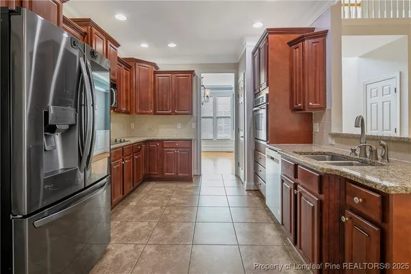 a kitchen with stainless steel appliances granite countertop a refrigerator a stove and a sink