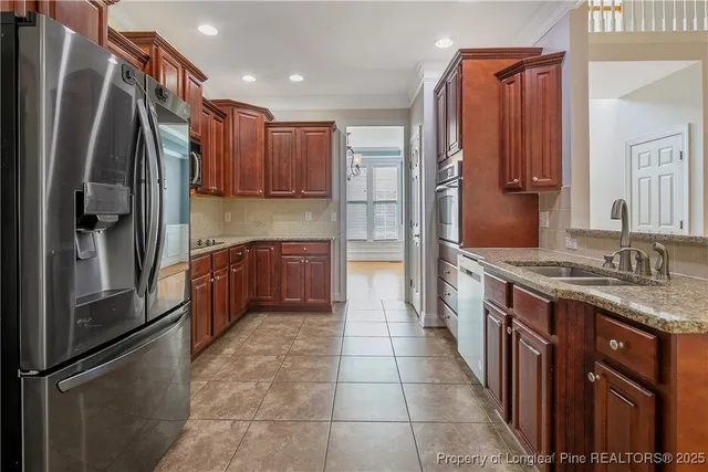 a kitchen with stainless steel appliances granite countertop a refrigerator a stove and a sink