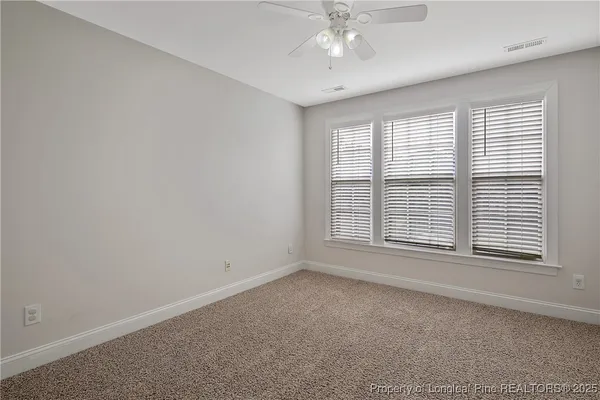 a view of an empty room and a chandelier fan