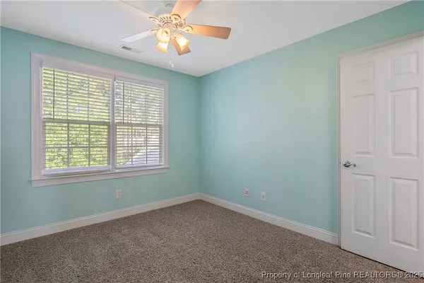 an empty room with a fan and a chandelier fan