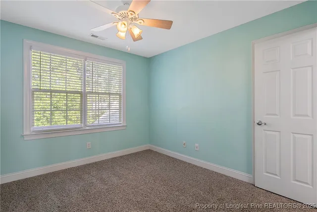 an empty room with a fan and a chandelier fan