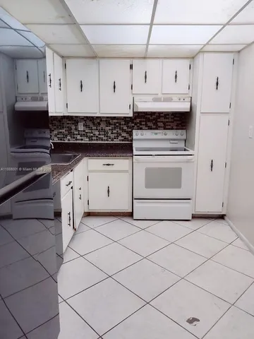 a kitchen with stainless steel appliances a stove and white cabinets
