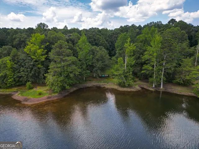 a view of a patio with a table and chairs under an umbrella with large trees