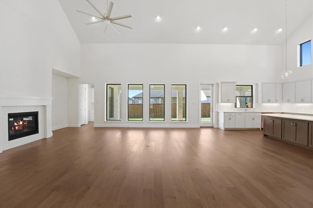 4626 Rillstone Road Midlothian, TX 76065 - Photo 5 of 40 Unfurnished living room with high vaulted ceiling, plenty of natural light, a tiled fireplace, recessed lighting, and dark wood-style floors