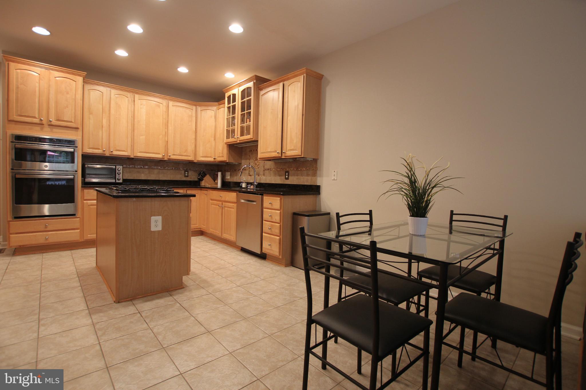 8532 Barrow Furnace Lane Lorton, VA 22079 - Photo 13 of 33 a kitchen with stainless steel appliances granite countertop a stove top oven a sink a dining table and chairs