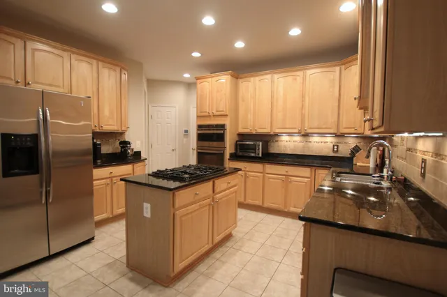 a kitchen with stainless steel appliances granite countertop a stove a sink and a refrigerator