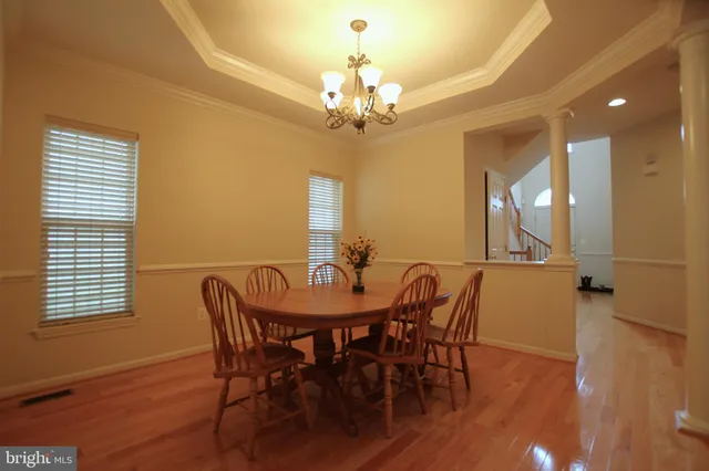 a view of a a dining room with furniture a chandelier and wooden floor