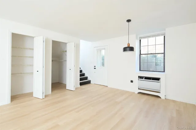 a view of an empty room with closet and windows