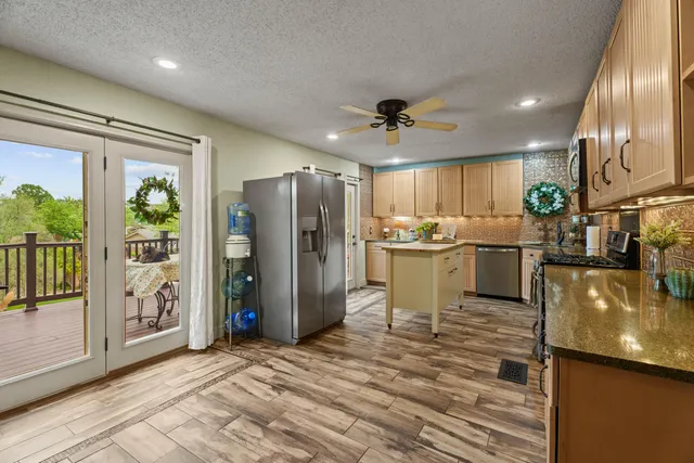a kitchen with stainless steel appliances granite countertop a refrigerator a stove and a sink with wooden floor