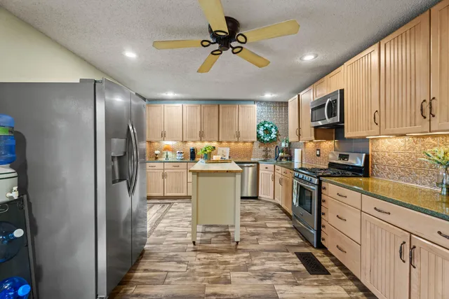 a kitchen with a refrigerator a stove top oven a sink dishwasher and a refrigerator with wooden floor