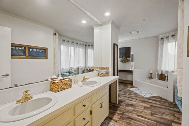 a bath room with a sink double vanity granite tub shower and a mirror