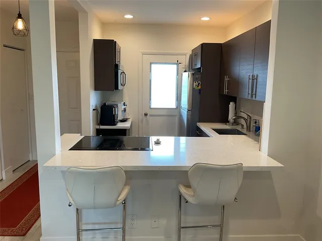 a kitchen with stainless steel appliances kitchen island granite countertop a refrigerator and a sink
